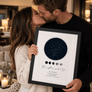 Couple kissing while holding a personalised star map print in a cozy setting.