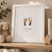 Personalised baby footprint foil print with name and date in a white frame.
