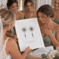 Bridesmaids and bride admire personalized flower print at wedding celebration.