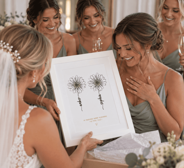 Bridesmaids and bride admire personalized flower print at wedding celebration.