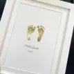 Personalised baby footprint foil print with name and date in a white frame.