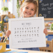 Child holding a personalised teacher thank you print with bees and names.